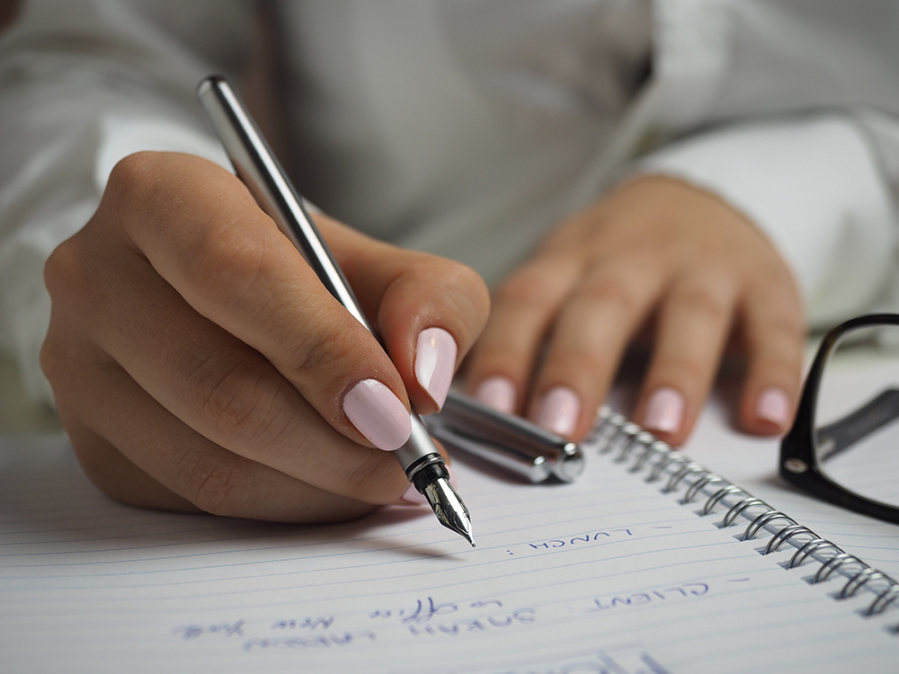 Image of someone with a beautiful manicure writing in a journal