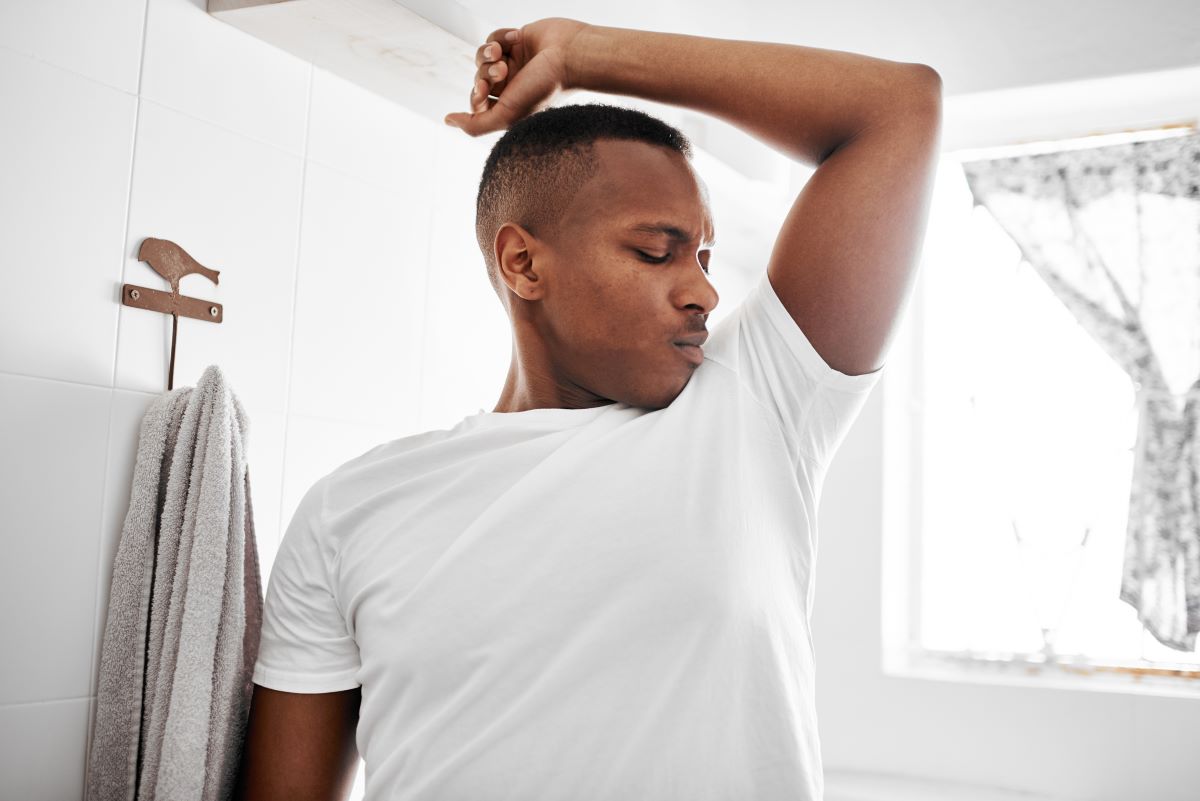 man testing body odors by smelling his underams