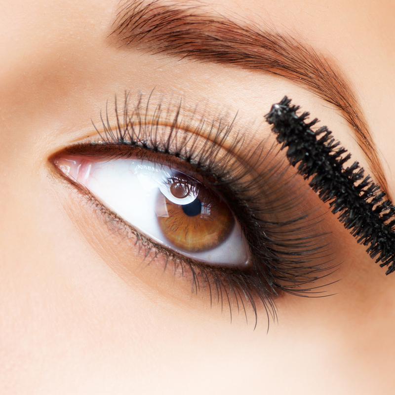 A woman applying mascara.